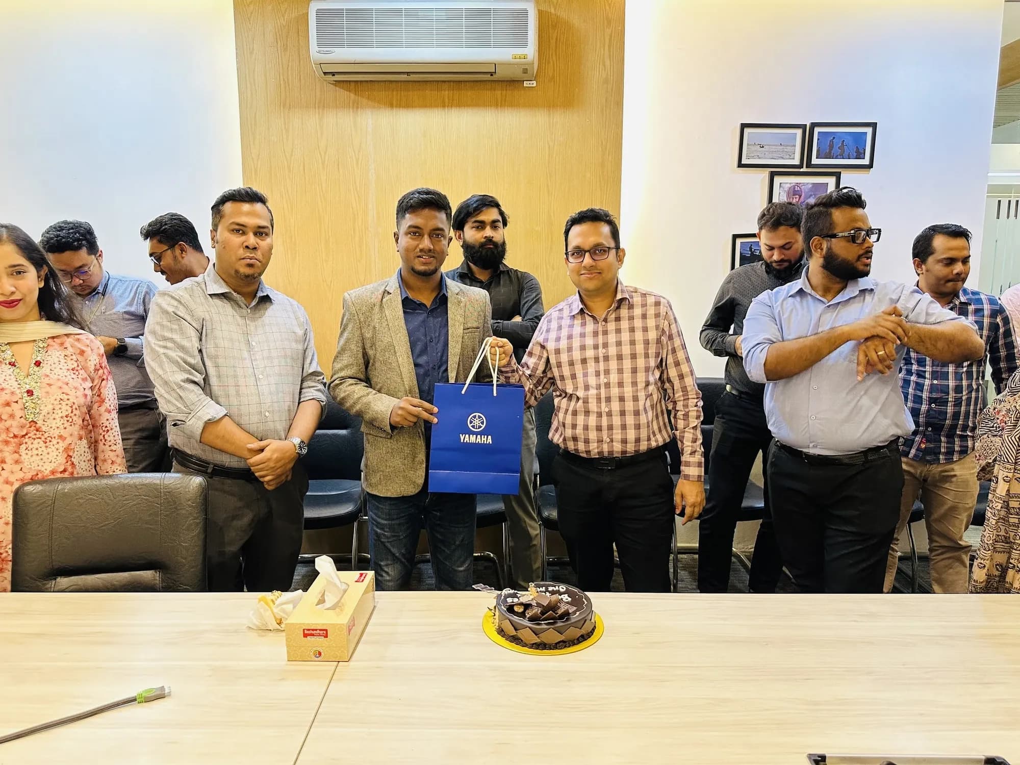 Colleagues gathered around a cake at an office celebration