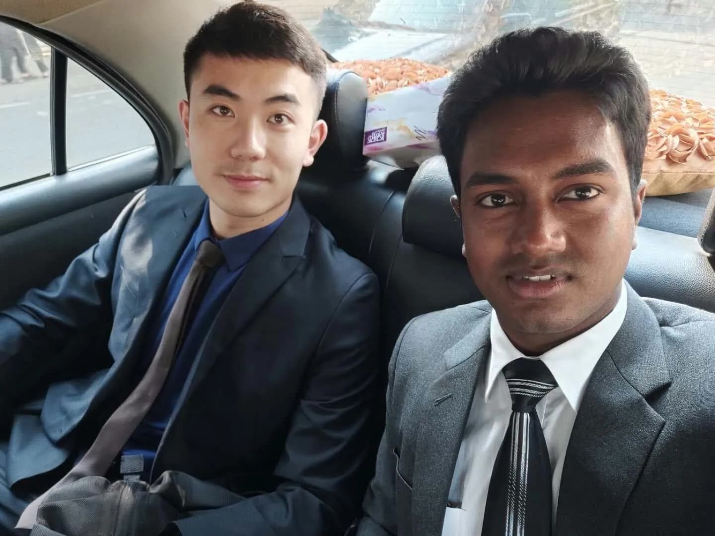 A car selfie with a colleague, both in suits